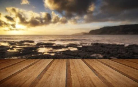 Stunning landscape ocean at sunset dramatic clouds with wooden planks floor Stock Photos