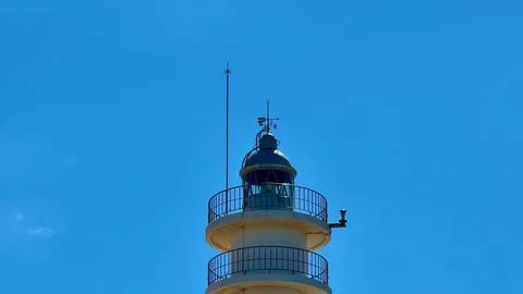A Stunning Lighthouse Standing Tall Underneath a Peaceful, Clear Blue Sky at Sea Stock Photos