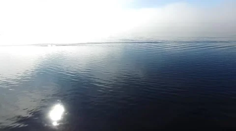 Stunning low aerial with reflection of sun in the water Stock Footage 53411340