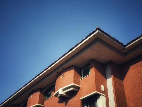 A stunning low-angle shot of a red brick building against a bright blue sky. Stock Photos