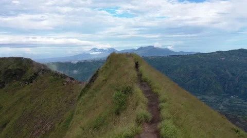 Stunning Man Running on Mountain Top Ridge Line Hands Up Aerial Drone Shot Bali Stock Footage 143833877