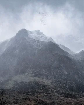 Stunning moody dramatic Winter landscape image of snowcapped Y Garn mountain  Stock Photos