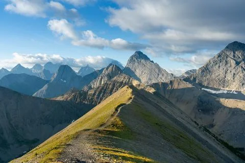 A stunning mountain range with clear blue skies and scattered clouds above. Stock Photos