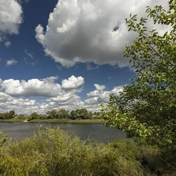 Stunning panoramic view of a large lake with forested banks and a distant vil Stock Photos