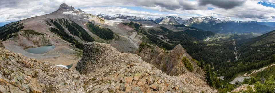 Stunning panoramic view of mountain range with lush valleys and glacial lak.. Stock Photos