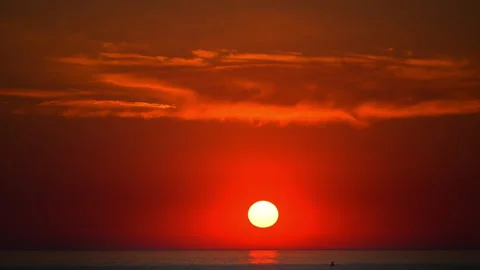 Stunning red sunset over calm sea with glowing sun and dramatic clouds Stock Footage 335303474