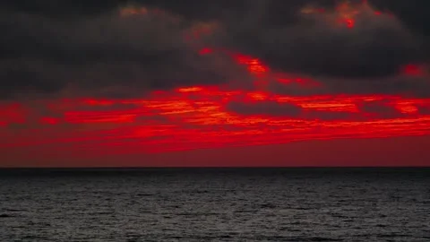 Stunning red sunset over the ocean with dramatic clouds in 4k Video stock 282472681