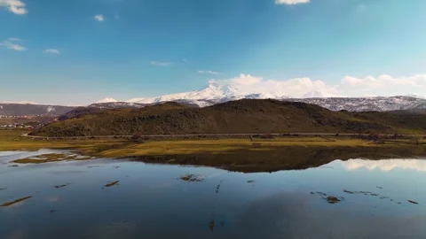 Stunning reflection of snowy mountains and clouds on a calm lake surface, aerial Stockbeeldmateriaal 332723595