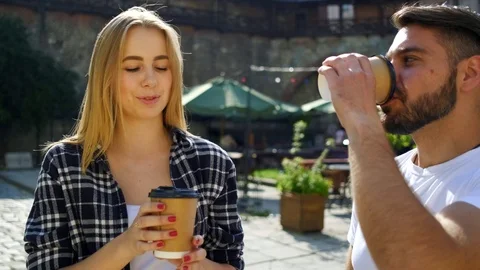 Stunning smiling young people drinking coffee on the street and talking to each  Stock Footage 112355823