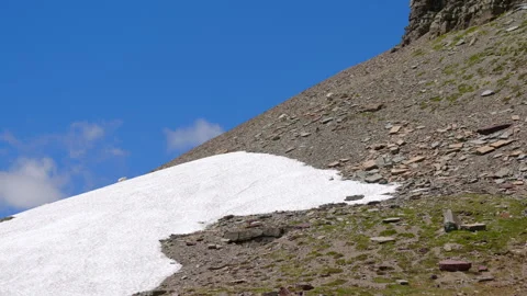 A stunning snow patch rests meticulously on a mountain slope under a beautiful Video stock 313561900