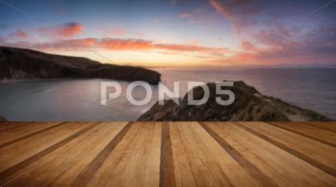 Stunning Summer sunrise over calm ocean landscape with wooden planks floor Stock Photos