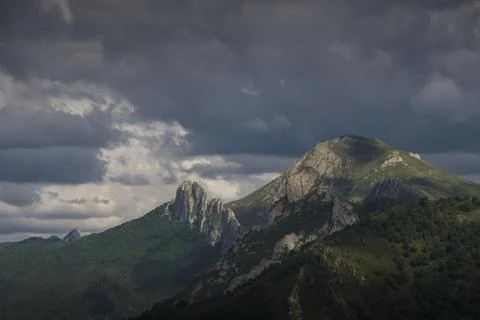 Stunning sun rays shine through a cloudy sky on mountain peaks 스톡 사진