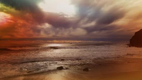 Stunning sunset and dramatic clouds across ocean waves on the shore. Stock Photos