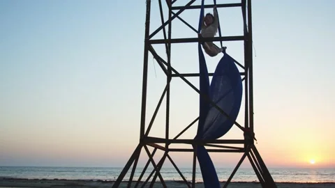 Stunning sunset in the background of a young lady doing aerial silks outdoors 4k Stock Footage 143246773