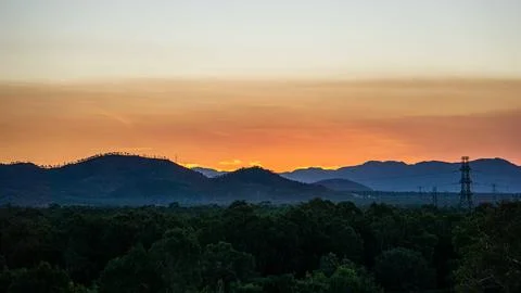 A stunning sunset casts its warm glow over rolling hills, creating a breath.. Stock Photos