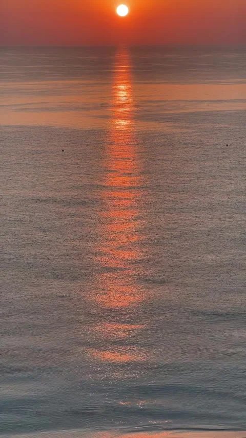 A stunning sunset casts vibrant colors over a calm sea, creating beautiful Stock Footage 306082341