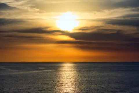 Stunning sunset in a dramatic sky above a serene, calm ocean Stock Photos