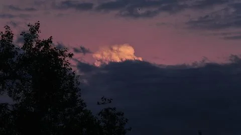 Stunning sunset landscape with cumulus cloud glowing golden light against dark Stock Photos