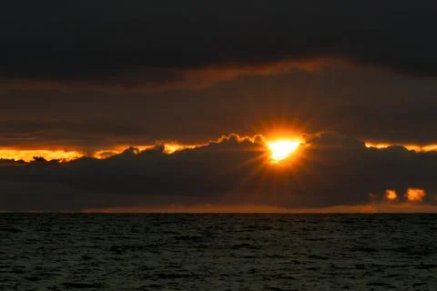 Stunning sunset landscape with rays emerging from clouds over the ocean Photos