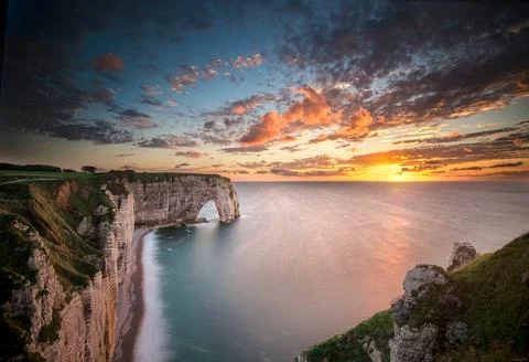 Stunning sunset over the dramatic cliffs and arch at Etretat, France during Stock Photos