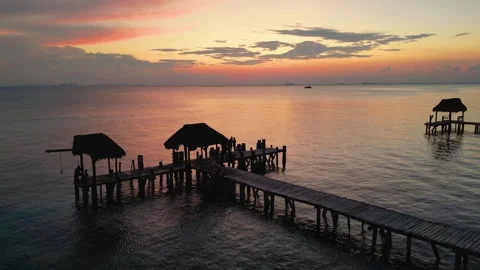 Stunning Sunset Over Isla with Silhouetted Pier and Thatched Roofs Stock Footage 324502863