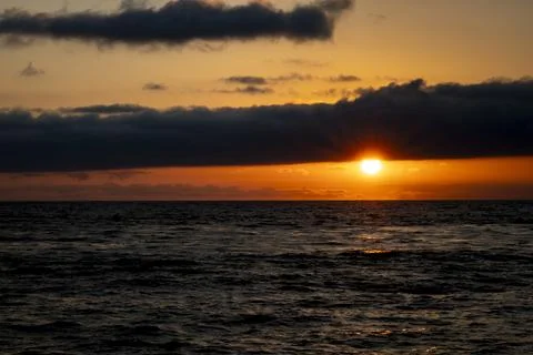 Stunning sunset over the ocean with dramatic clouds and vibrant colors Photos
