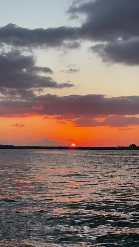 Stunning sunset over the ocean with vibrant orange sky and dark clouds Vidéo 334084885