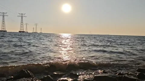 Stunning sunset over the ocean with a vibrant red sun and calm waves washing Vídeos de archivo 334163436