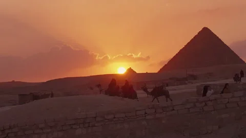 Stunning sunset over the pyramids with silhouettes of camels and their ride.. Stock Footage 287021058