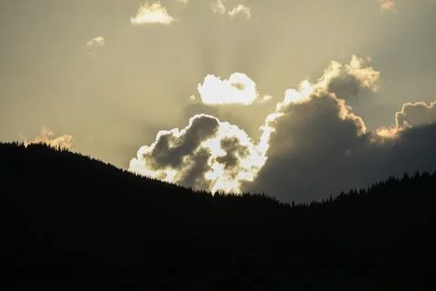 Stunning sunset with rays of sunlight breaking through clouds over mountain Stock Photos