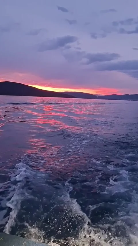 Stunning sunset view over the calm sea with a boat wake in the foreground and Vídeos de archivo 334163163