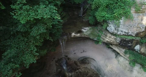 Stunning tilt down shot of hidden cave in the wilderness. Tiny spring is Stock Footage 109794052