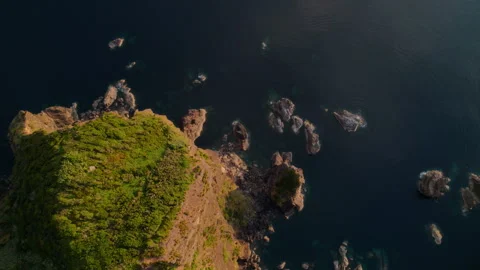Stunning top-down aerial drone view of a rugged volcanic headland surrounded by Vídeo Stock 335711092