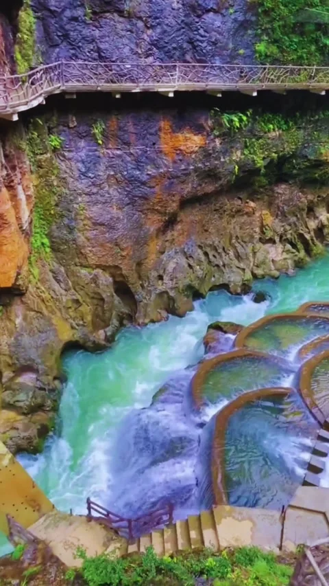Stunning Turquoise Waterfall Flowing Through Rocky Cliffs in 4K Stock Footage 314540348
