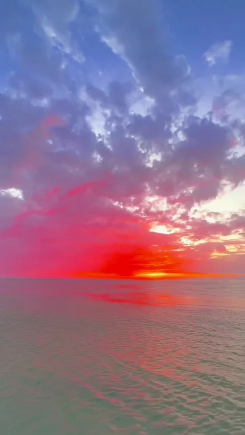 Stunning vibrant sunset over calm ocean waters with dramatic clouds Vidéo 334085046