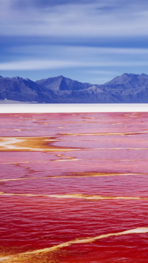 Stunning view of a red lake surrounded by mountains during a clear day Stock Footage 336991388