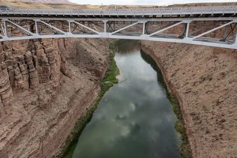 Stunning view of a river flowing under a bridge in a canyon during a cloudy d Stock Photos