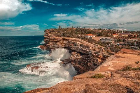 Stunning View of Rock Cliff next to the Ocean with Waves hitting Shore Stock Photos