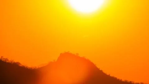 Stunning view of the sun setting or rising over rugged mountains, creating .. Stock Photos