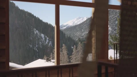 Stunning view of a sunlit snowy mountain valley through the window of a cozy Stock-Footage 334869301