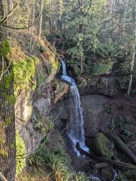 A stunning waterfall cascading down rugged rocks into a serene pool below, .. Stock Photos