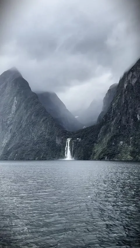 Stunning waterfall cascading down steep mountains into milford sound, new Stockbeeldmateriaal 334085037