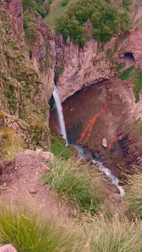 A stunning waterfall flows gracefully, surrounded by steep rocky cliffs and lush 動画素材 312818574