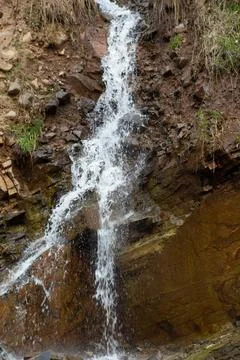 A stunning waterfall plunges down a rugged cliff face in a natural environment. Stock Photos