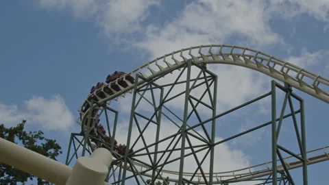 Stunning wide view of people in a rollercoaster going down and through a double Video stock 337745305
