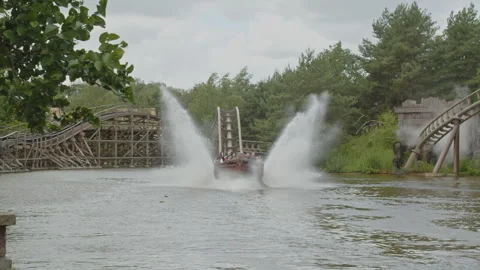 Stunning wide view of rollercoaster cart splashing down in a pond of water of a Video stock 338026143