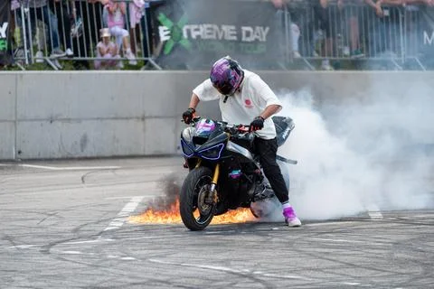 Stunt driver perform burnout in fire with his motorbike Stock Photos