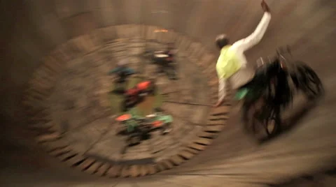 Stuntman riding motorbike around wooden wheel known as the wall of death Stock Footage