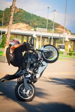 Stuntrading on motorcycle stunts while driving on the rear wheel of a Willie Stock Photos