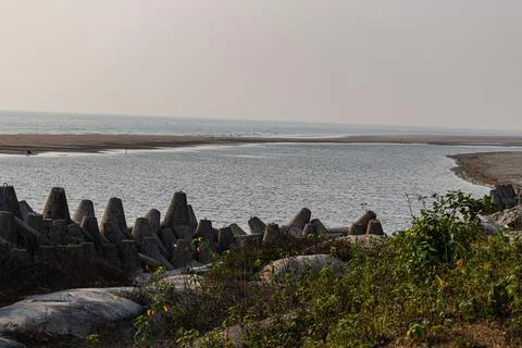Sturdy grey tetrapod wave breakers lined along the coast protecting sandy sh Stock Photos